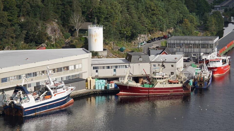 HER BRANT DET: Det er i bygget bak den røde båten midt i bildet at det brøt ut brann som nå skal være slukket.